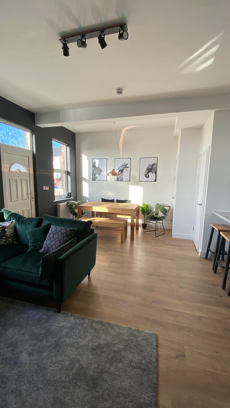 Open-plan living and dining space with green sofa and wooden table
